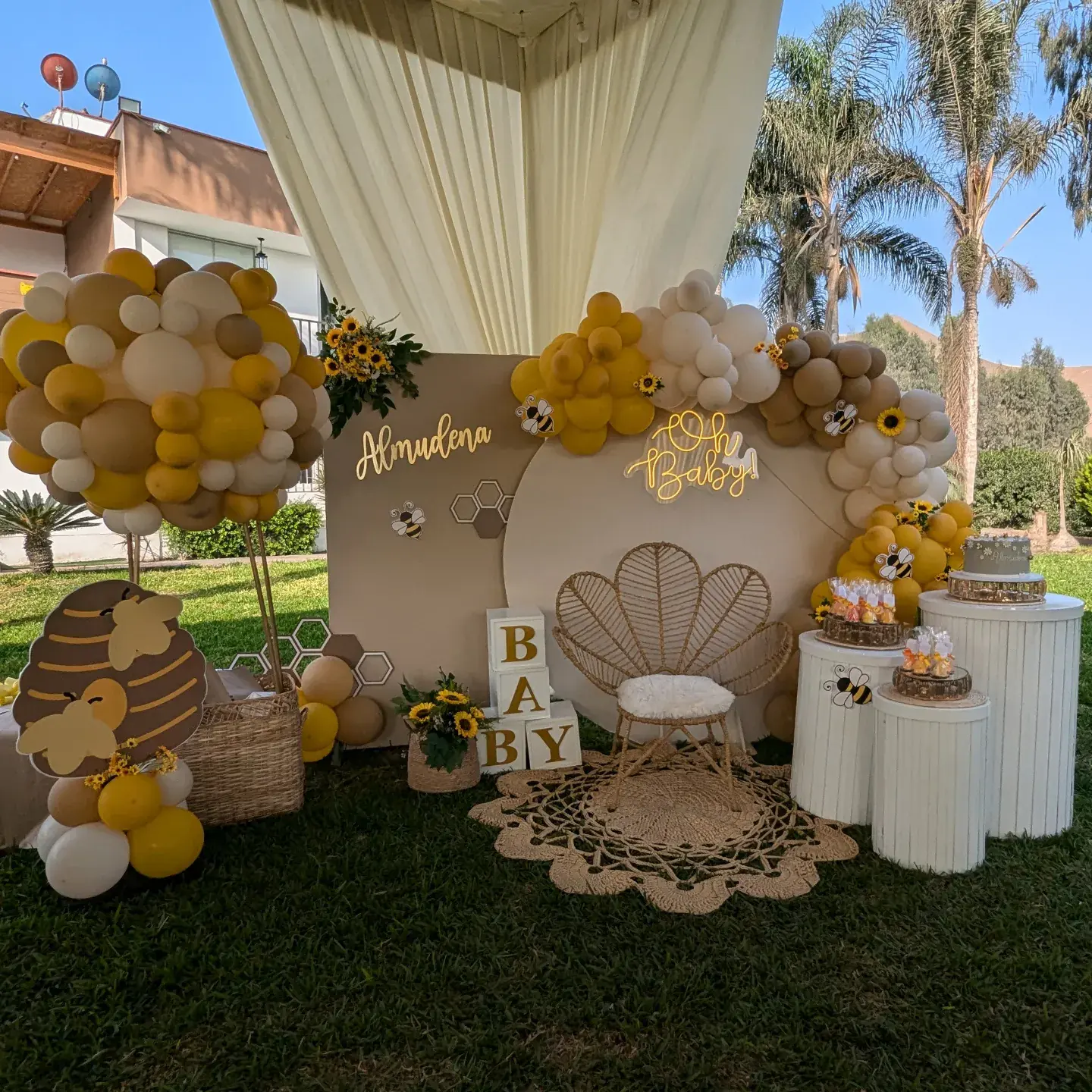 Fondo decorado con globos dorados y blancos para un baby shower en el jardín