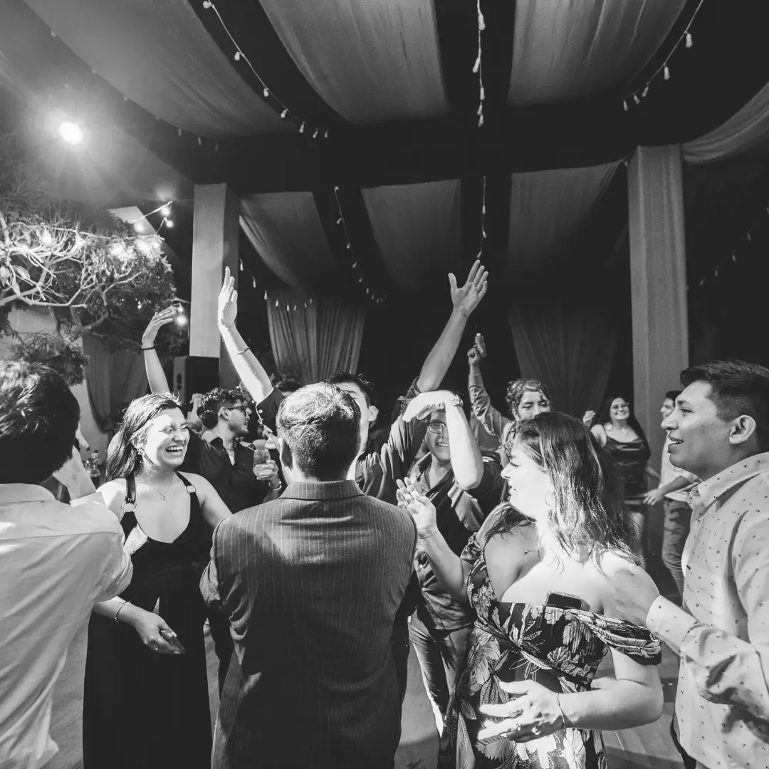 Invitados bailando con los brazos en alto, fotografía en blanco y negro