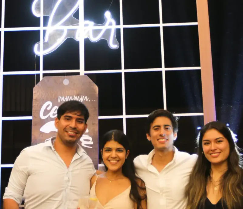 Cuatro amigos brindando frente a la barra durante una fiesta de graduación