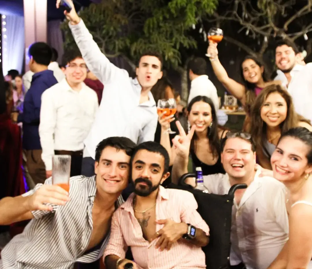 Grupo grande de egresados celebrando juntos con copas en alto en la fiesta de promoción